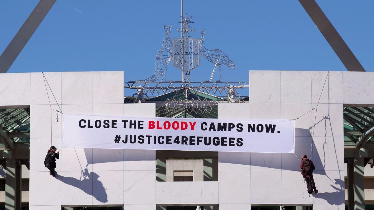 Protesters unfurl a banner at the Australian Parliament in Canberra on Dec. 1.