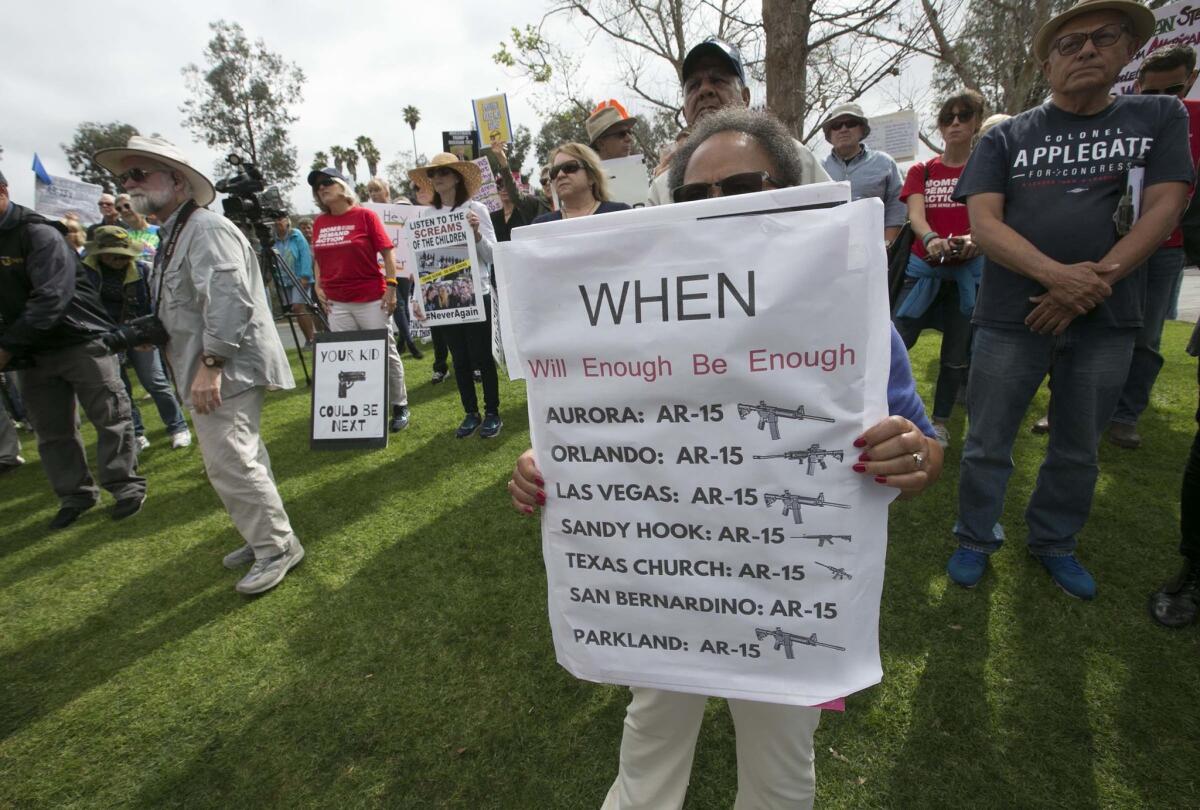 Edith Jones holds a sign tallying gun deaths. (John Gibbins / San Diego Union-Tribune)