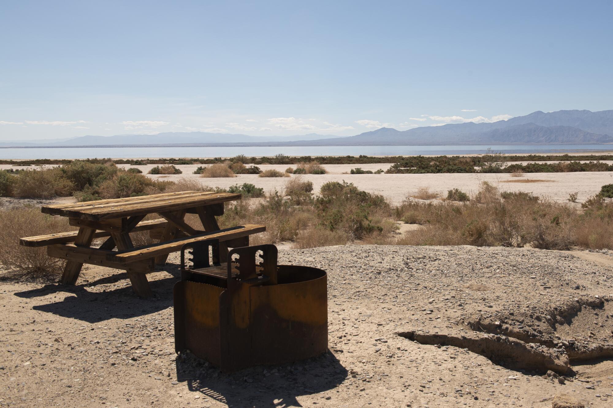 An empty picnic table, left, with a view of the sea and mountains in the distance