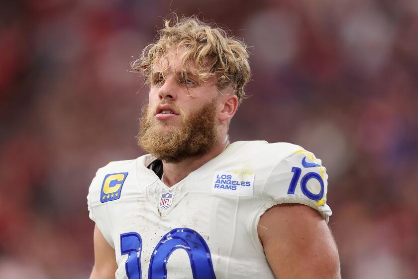 Rams receiver Cooper Kupp walks on the field with his helmet off.