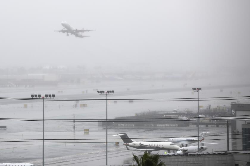 An Air Canada jet headed for Toronto takes off to the east from San Diego International Airport as fog rolls in on Dec. 4, 2019.