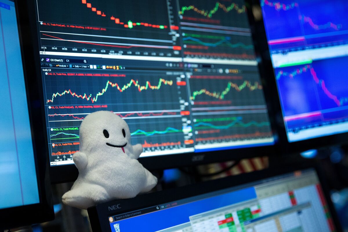 A plush toy of Snapchat's ghost mascot sits on a trader's desk at the New York Stock Exchange.