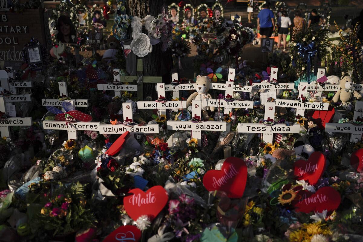 Flowers and hearts are piled around crosses with the names of the victims killed in a school shooting.