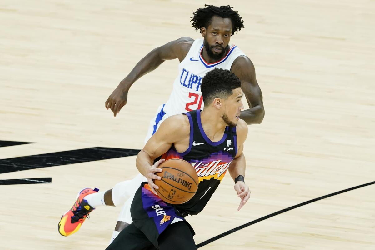 Suns guard Devin Booker bring the ball up court while defended by Clippers guard Patrick Beverley.