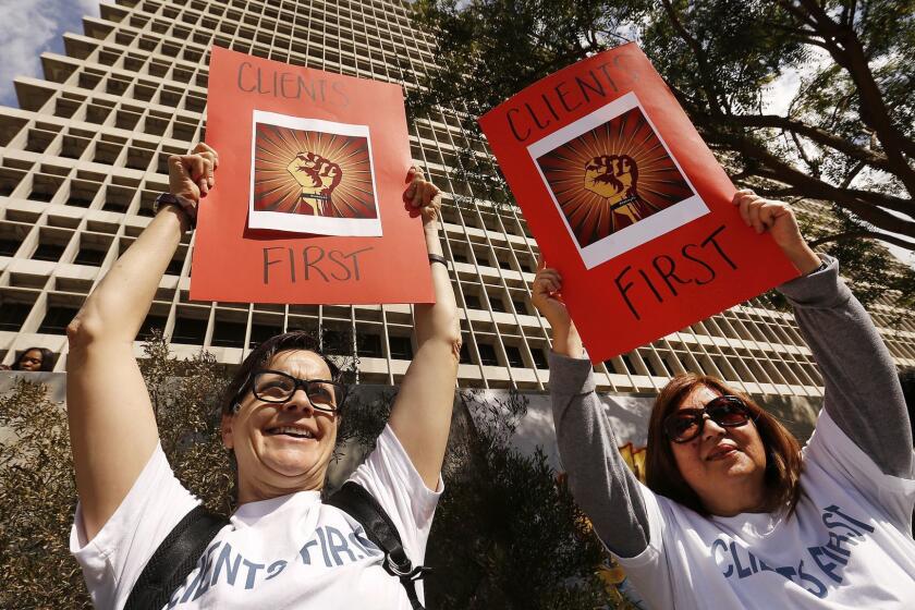 LOS ANGELES, CA â FEBRUARY 12, 2018: Deputy Public Defenders Jan Datomi, left, and Susan Roe, right, hold signs as deputy public defenders and supporters gathered at a rally in Grand Park Monday February 12, 2018 in opposition of their new boss, Nicole Davis Tinkham. In recent days, hundreds of people in the office have signed a letter and petition asking for her ouster and many have taken to wearing wristbands that read #notmyPD". (Al Seib / Los Angeles Times)