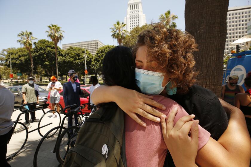 LOS ANGELES, CA - JULY 20: Sunflower Haze, right, hugs Mike L. After she spoke during a news conference outside LAPD Headquarters to announce lawsuits against the LAPD over its alleged targeted attacks against journalists and activists during anti-transgender and counter protests associated with Wi Spa, a Koreatown business with a trans-inclusive policy that gained notoriety when a customer filmed herself complaining about a trans woman in the women's area of the establishment, contact says. Justice X contends that LAPD officers ``illegally fired deadly projectiles at defenseless protesters, attacked innocent protesters with batons and other weapons and were harboring white supremacists in violation of constitutional rights.'' LAPD Headquarters on Tuesday, July 20, 2021 in Los Angeles, CA. (Al Seib / Los Angeles Times).