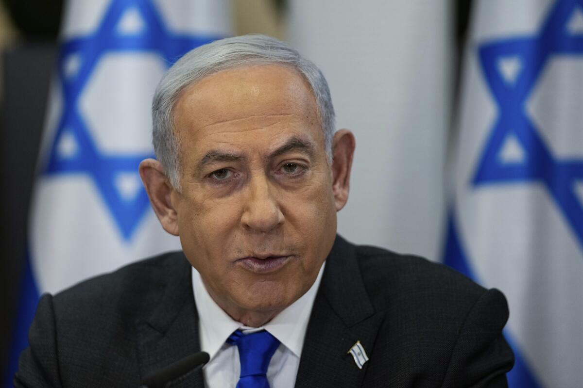 Benjamin Netanyahu speaks in front of Israeli flags.
