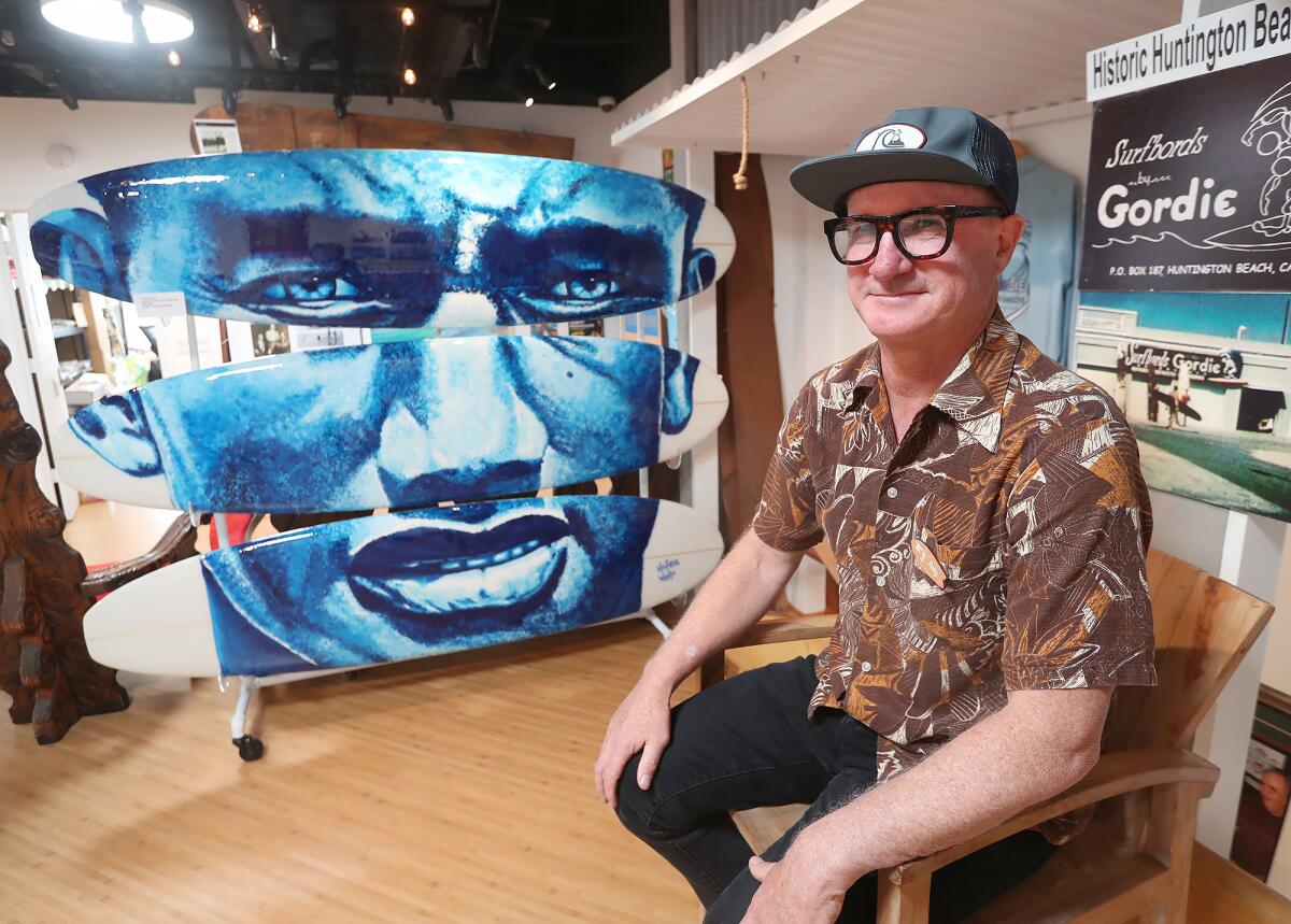 Ricky Blake sits with Victoria White's "Duke," at the Huntington Beach International Surfing Museum.