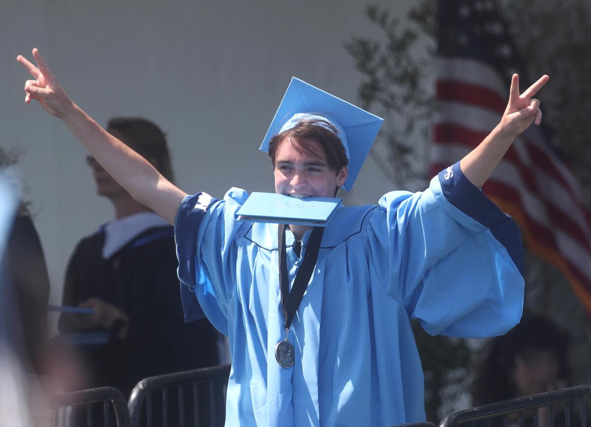 A happy graduate throws two peace signs after receiving his diploma.