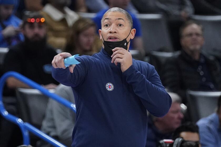 Los Angeles Clippers head coach Tyronn Lue pulls his mask down to direct his team in the first half.