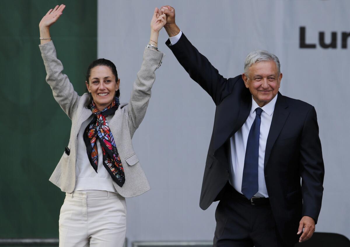 Mexican President Andrés Manuel López Obrador and Claudia Sheinbaum raising their hands together above their heads.