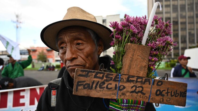 A man holds a cross honoring a relative killed in Guatemala's civil war. Hundreds marched in Guatemala City on Monday, the 20th anniversary of a truth commission's report on the war. They protested an amnesty bill for those accused of human rights violations during the war.