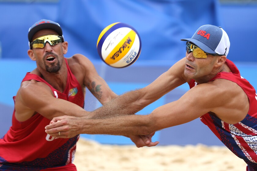 Phil Dalhausser and Nick Lucena both reach for the ball, which is midair between them.