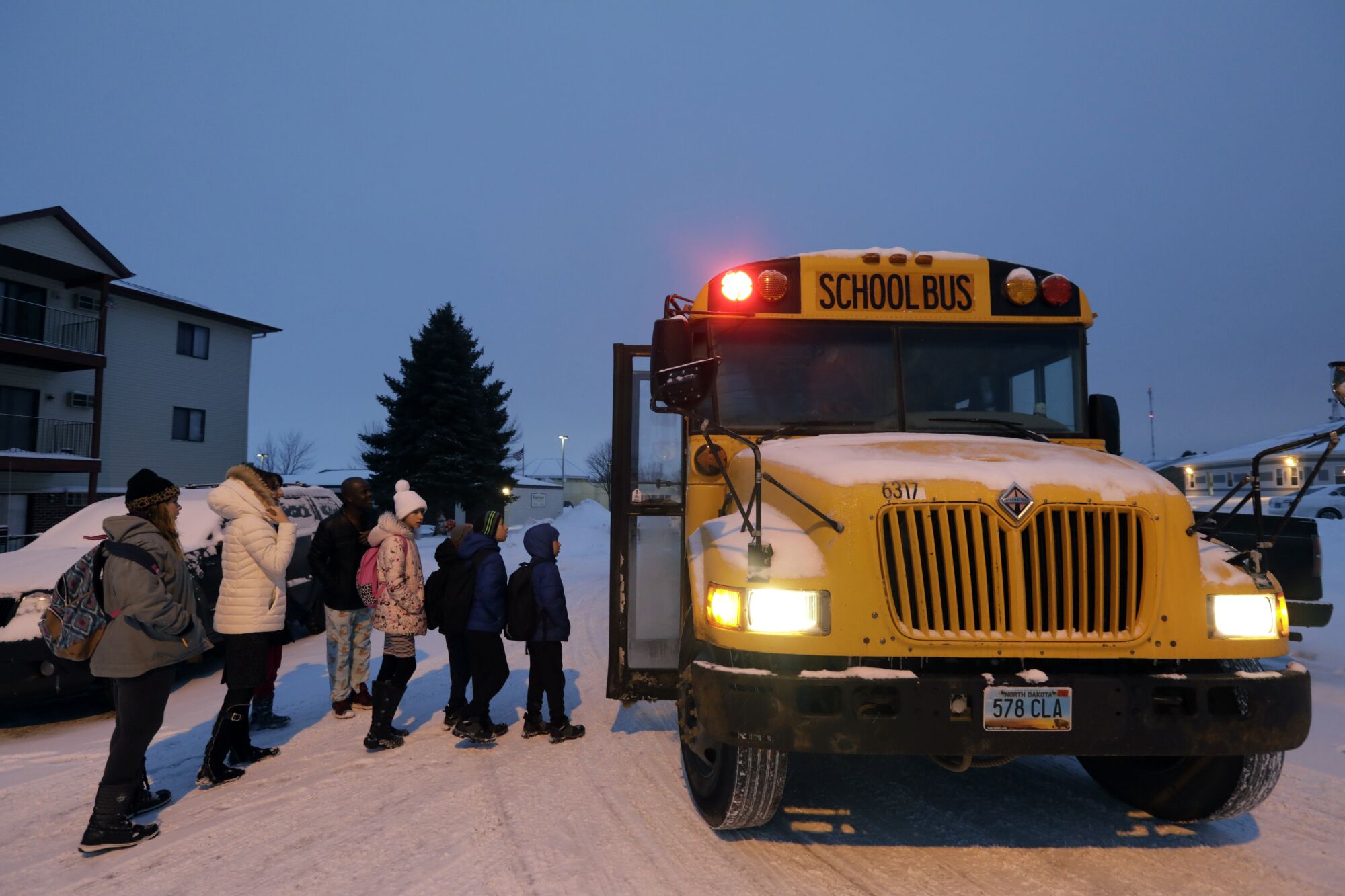 Yuliia Kulybchuk, age 33, second from left, is mother of five children who with her husband Anatolli Kulybchuk immigrated from Ukraine to North Dakota in 2019. They are religious minority. Yuliia sees four of her children onto the school bus in the morning. Everyone in the family must now learn to speak English.
