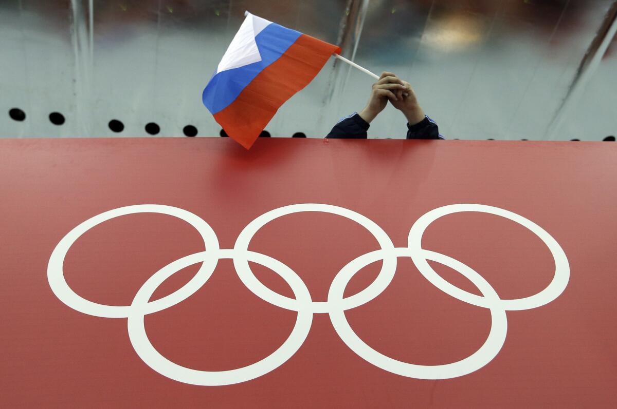 A Russian fan holds the country's flag over the Olympic rings during the 2014 Winter Olympics in Sochi.