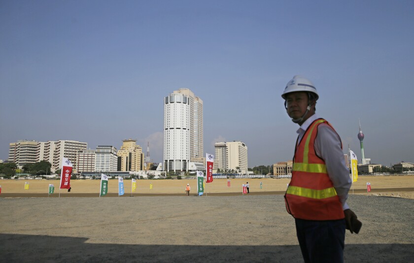 FILE - In this Jan. 2, 2018, file photo, a Chinese construction worker stands on land that was reclaimed from the Indian Ocean for the Colombo Port City project, initiated as part of China's ambitious One Belt One Road initiative, in Colombo, Sri Lanka. Sri Lanka’s top court , Tuesday, May 18, 2021, has ordered that some provisions of a legislation to set up a powerful economic commission in a Chinese-built port city violate the constitution and require approval by a public referendum to become law. (AP Photo/Eranga Jayawardena, File)