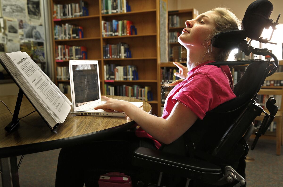 Lilly leans back for a few moments during study hall at the La Jolla High library. She has difficulty keeping her head upright for more than a few moments or speaking more than a few breathless words at a time. Her keyboard and smartphone have become her voice, enabling her to compose manuscripts and communicate with teachers and friends.