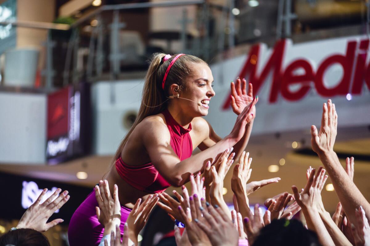 A fitness influencer gives out high fives from the stage.
