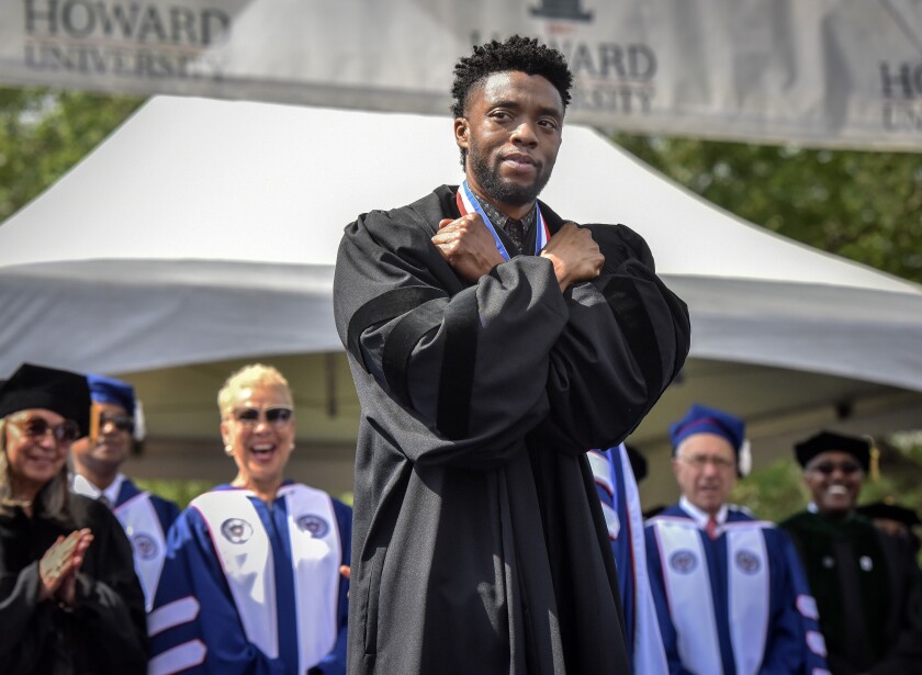 Chadwick Boseman gives a Wakanda salute in a graduation gown