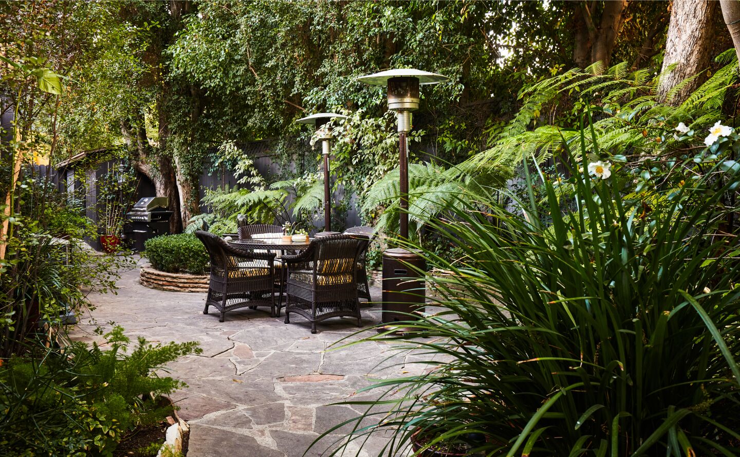 Dense landscaping surrounds a small dining area in the back.