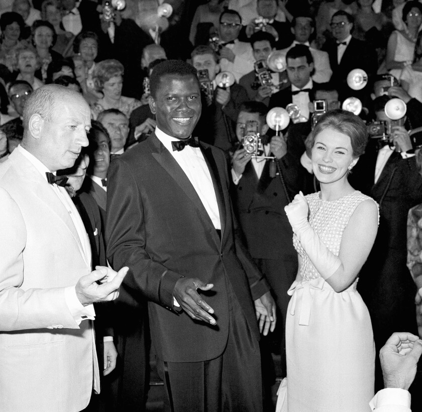 Sidney Poitier in a tuxedo with photographers behind him