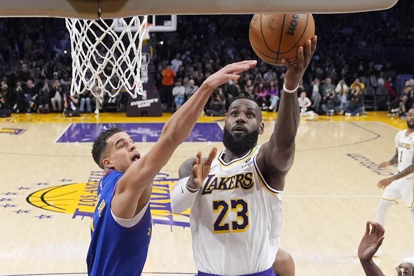 Los Angeles Lakers forward LeBron James, right, scores as Denver Nuggets forward Michael Porter Jr.
