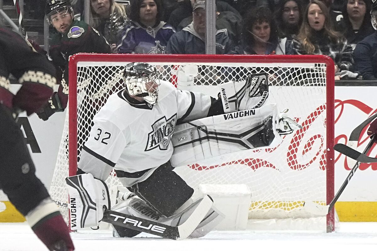 Kings goaltender Jonathan Quick, right, makes a glove save in front of Arizona Coyotes center Nick Schmaltz.