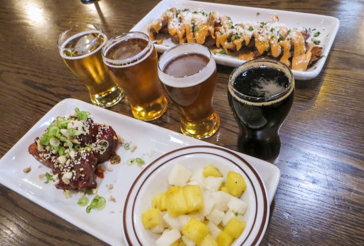 A round of tasters and plates of crispy pork belly and potato rounds from Mastiff Sausage Co. at North Park Beer Co. (Irene Lechowitzky)