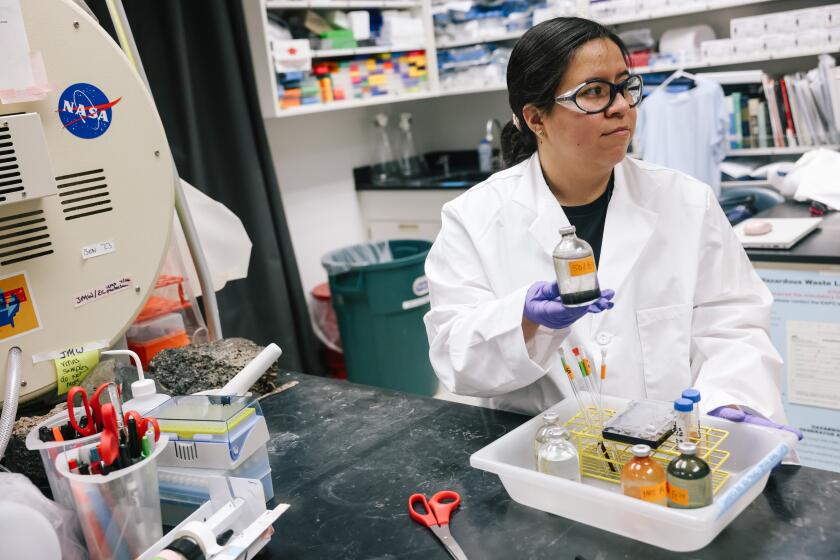 Pasadena, CA - May 29: Cathy Trejo holds different liquids that are meant to help understand early earth and possibly other planets inside the Origins and Habitability Lab for experiments at Jet Propulsion Laboratory on Wednesday, May 29, 2024 in Pasadena, CA. She is one of several students from California State University, Los Angeles who are interning at JPL's Origins and Habitability Lab through a grant that helps underrepresented students learn more about astrobiology and perform NASA-sponsored research. (Dania Maxwell / Los Angeles Times)