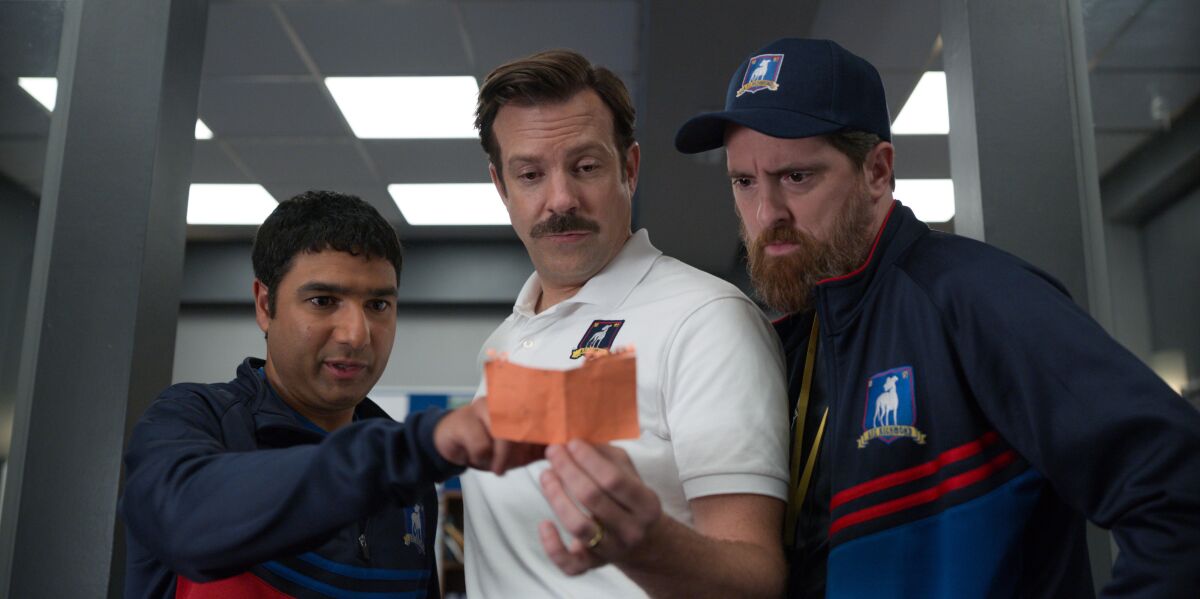 This image released by Apple TV Plus shows Nick Mohammed, from left, Jason Sudeikis, and Brendan Hunt in "Ted Lasso." The program was nominated for an Emmy Award for outstanding comedy series. Sudeikis was also nominated for outstanding lead actor in a comedy series and both Mohammed and Hunt were nominated for supporting actor in a comedy series. (Apple TV Plus via AP)