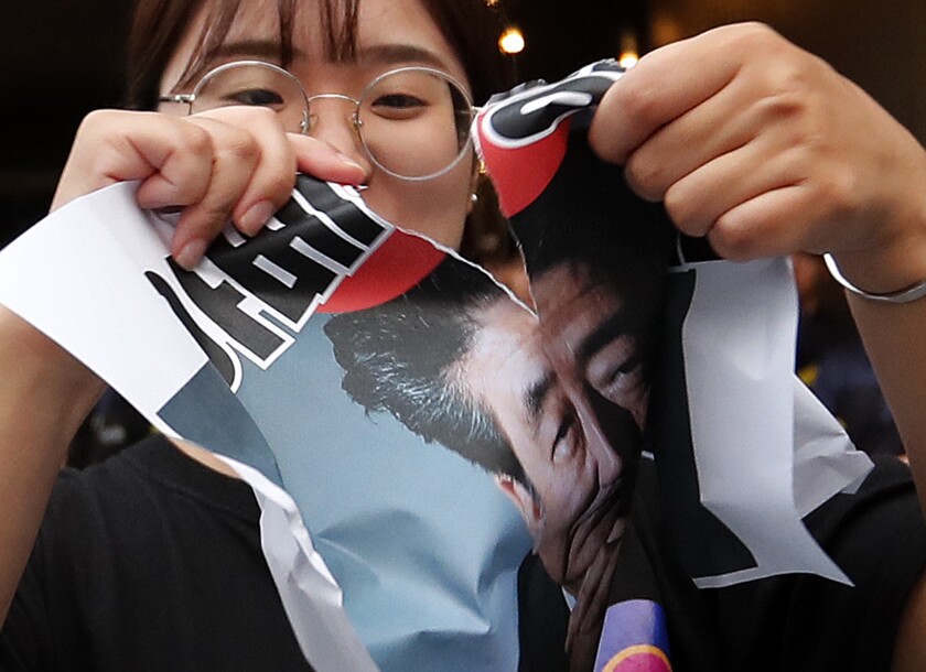 A protester tears an image of Japanese Prime Minister Shinzo Abe during a rally denouncing Japanese government's decision on their exports to South Korea, in front of the Japanese embassy in Seoul, South Korea on Thursday.
