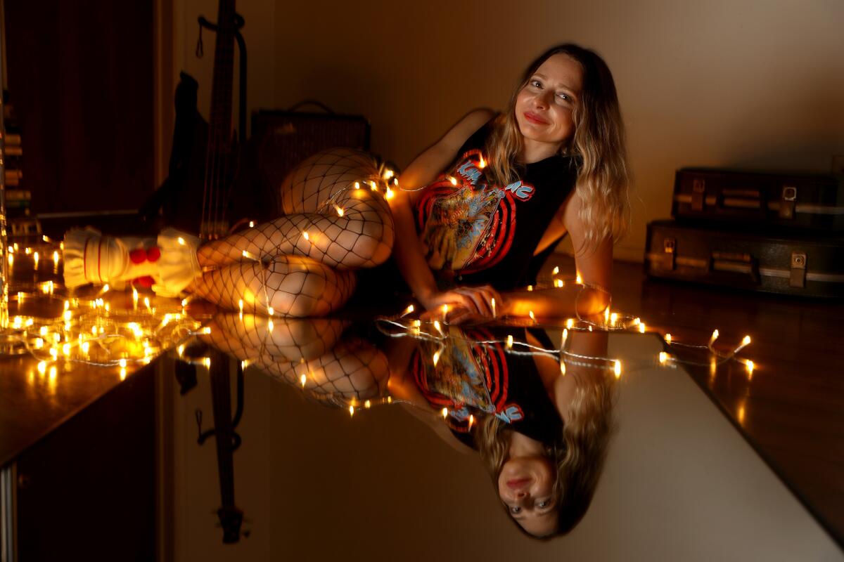 Woman lying down on a mirror draped in string lights