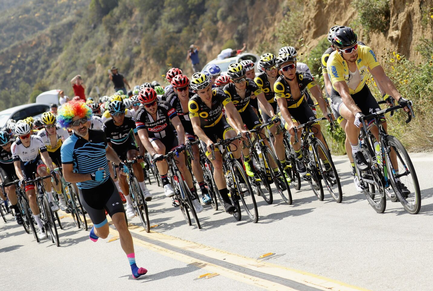 Peter Sagan (yellow jersey) rides in the peloton not far from a fan running down the road during the second stage of the Amgen Tour of California on May 16.