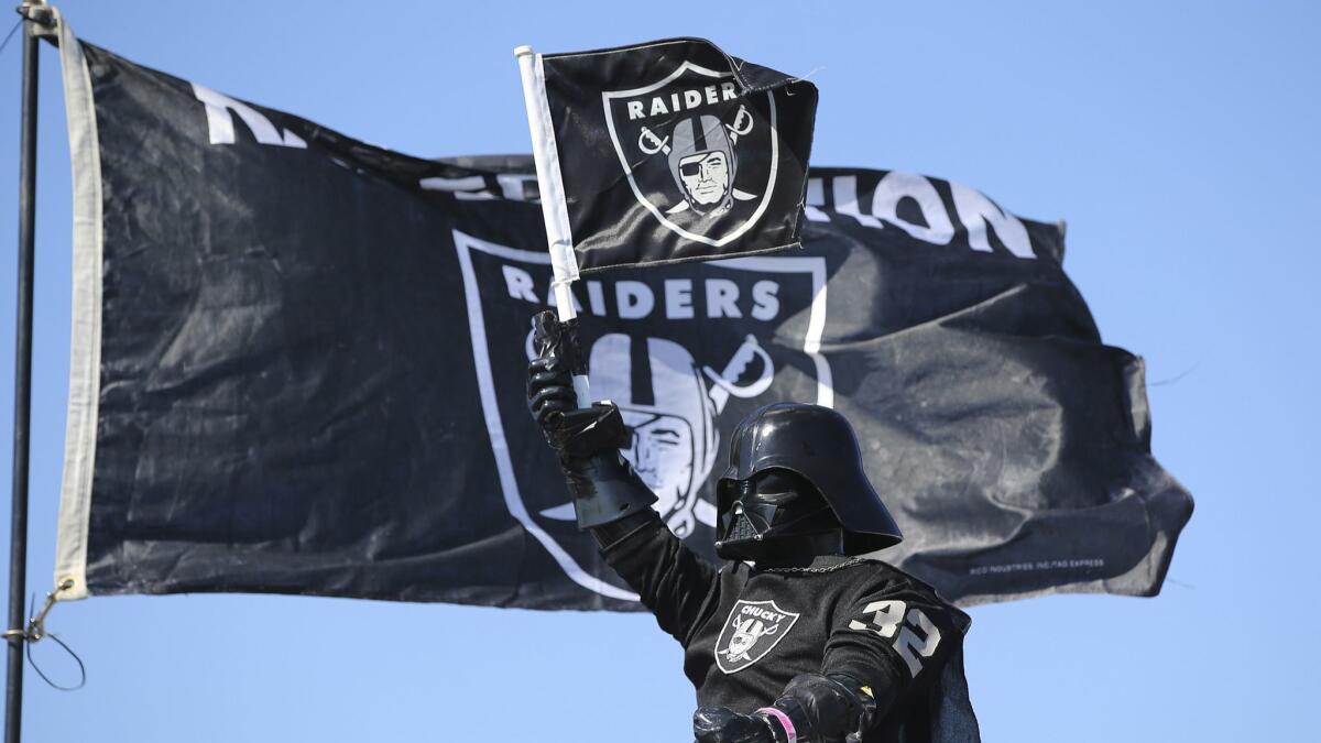 An Oakland Raiders fans holds up a flag while tailgating.
