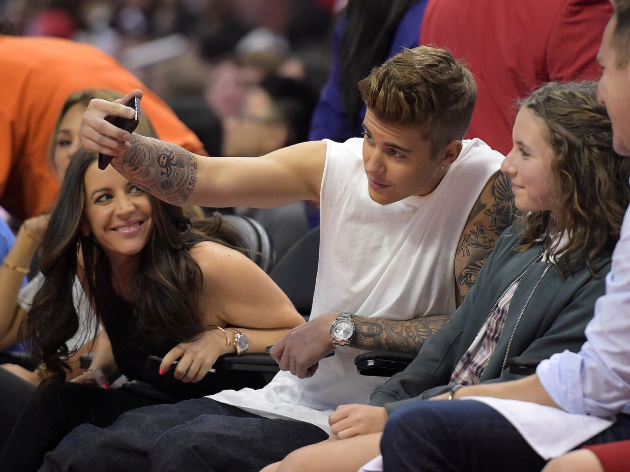 Singer Justin Bieber, center, takes a selfie with a young fan as he watches the Los Angeles Clippers play the Oklahoma City Thunder with his mother, Pattie Mallette, in the second half of Game 4 of the Western Conference semifinals on May 11, 2014, in Los Angeles.