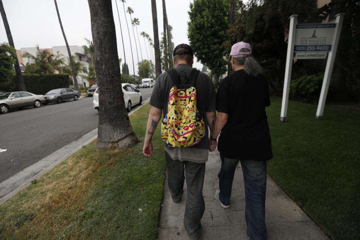 Husband and wife Larry and Tess Wynne walk from a shelter to the Glendale Galleria.