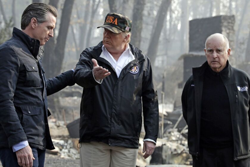 FILE - In this Nov. 17, 2018 file photo, President Donald Trump talks with Gov.-elect Gavin Newsom, left, as California Gov. Jerry Brown listens during a visit to a neighborhood impacted by the Camp wildfire in Paradise, Calif. For US governors, including 19 taking office early next year, fires, floods and other climate-related emergencies could become top policy concerns. For some, the concern is often trying to curtail global warming. But other leaders also have taken steps to mitigate damage from future disasters. (AP Photo/Evan Vucci, File)
