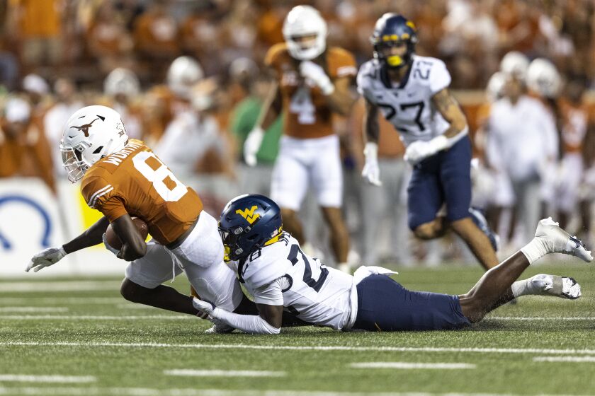 Texas wide receiver Xavier Worthy (8) is tackled by West Virginia defensive back Jacolby Spells (28) during the second half of an NCAA college football game Saturday, Oct. 1, 2022, in Austin, Texas. (AP Photo/Stephen Spillman)