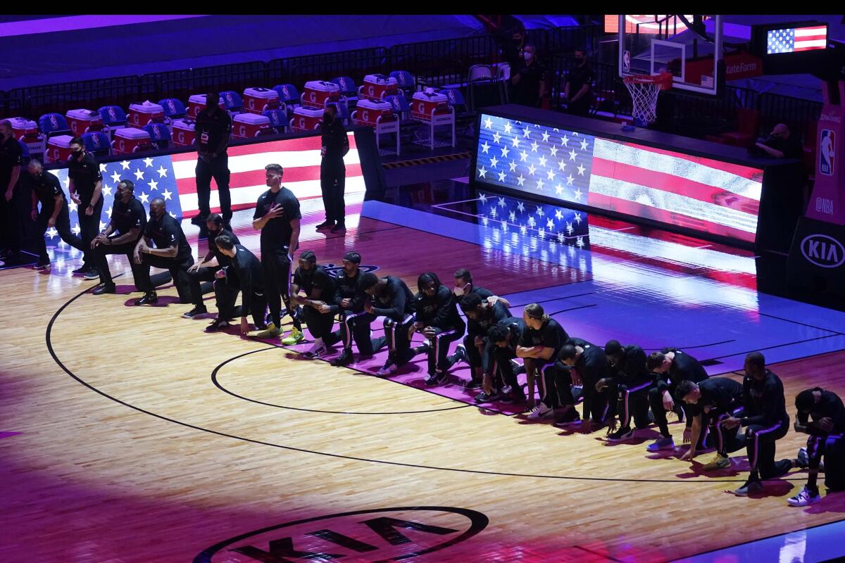 The Boston Celtics team kneels during the playing of the National Anthem.