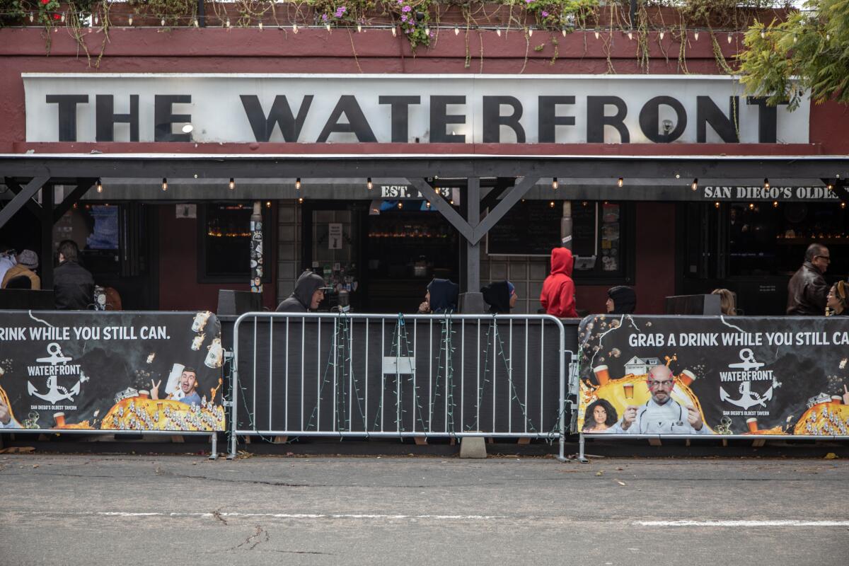 Diners at tables in front of Little Italy's The Waterfront Bar and Grill are separated from the street by metal barriers. 