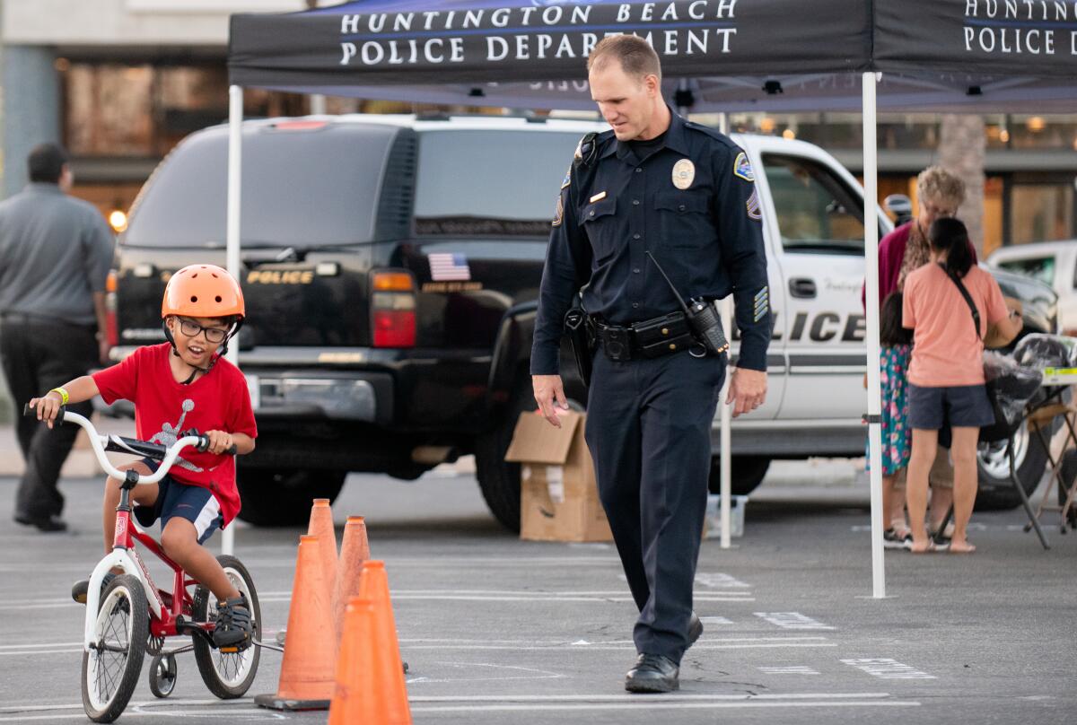 HBPD Sgt. Mike Thomas guides Toby Do, 5, through an obstacle course during the department's Bike Rodeo Tuesday.