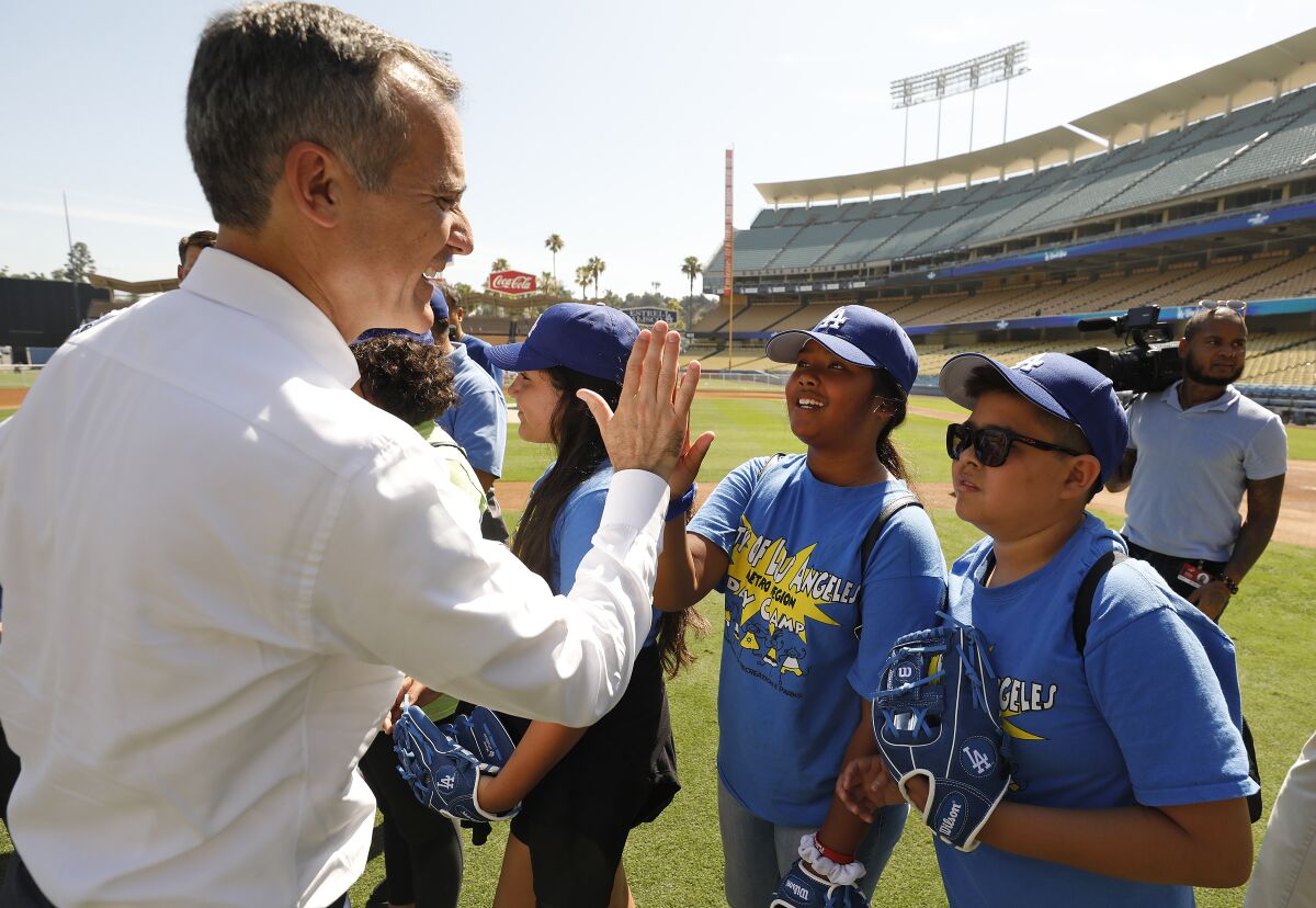 Los Angeles Mayor Eric Garcetti high-fives children on a baseball field