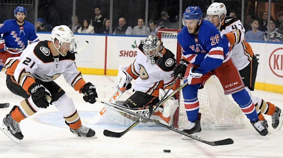 Ducks goalie John Gibson (36) deflects the puck as New York Rangers center Paul Carey (28) and Ducks center Chris Wagner (21) looks to control it during the second period on Tuesday.