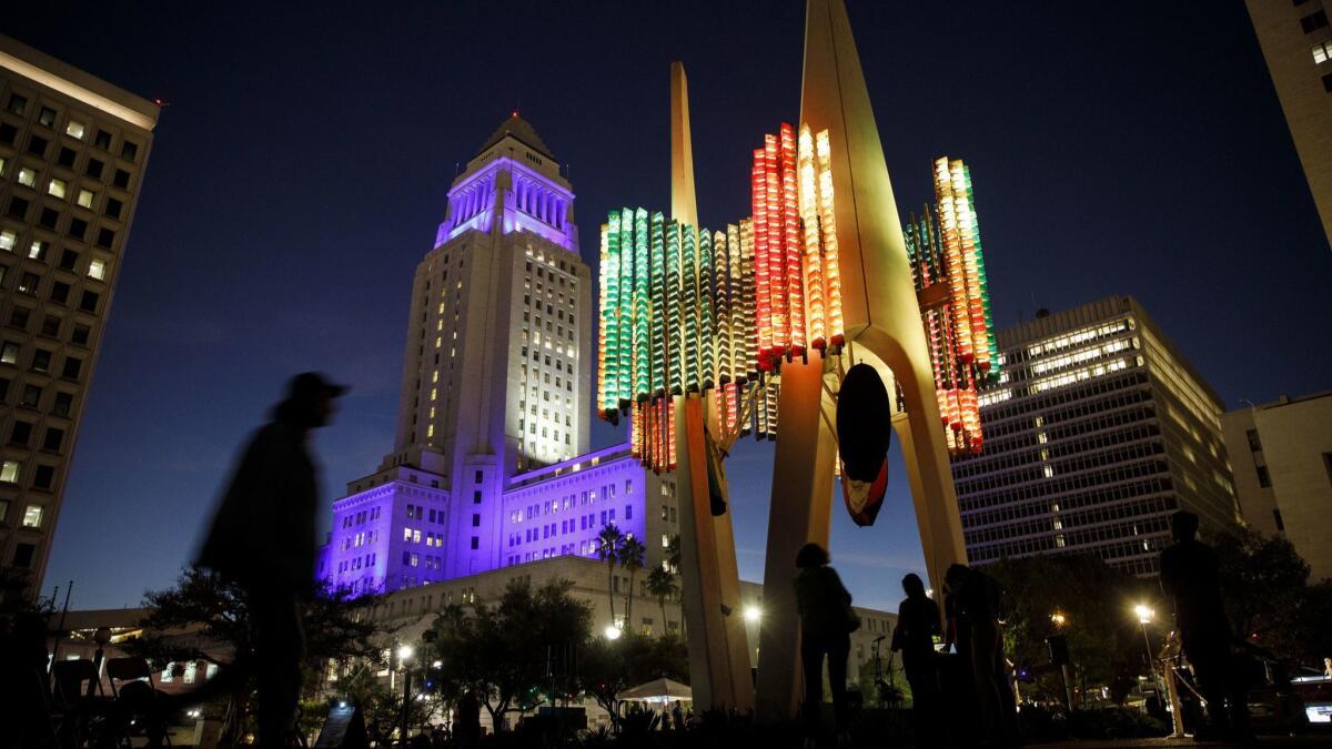 The colored LED lights of the Triforium public artwork in downtown Los Angeles glow beneath City Hall, itself bathed in Dodgers blue, during a Triforium Friday performance on Oct, 26.