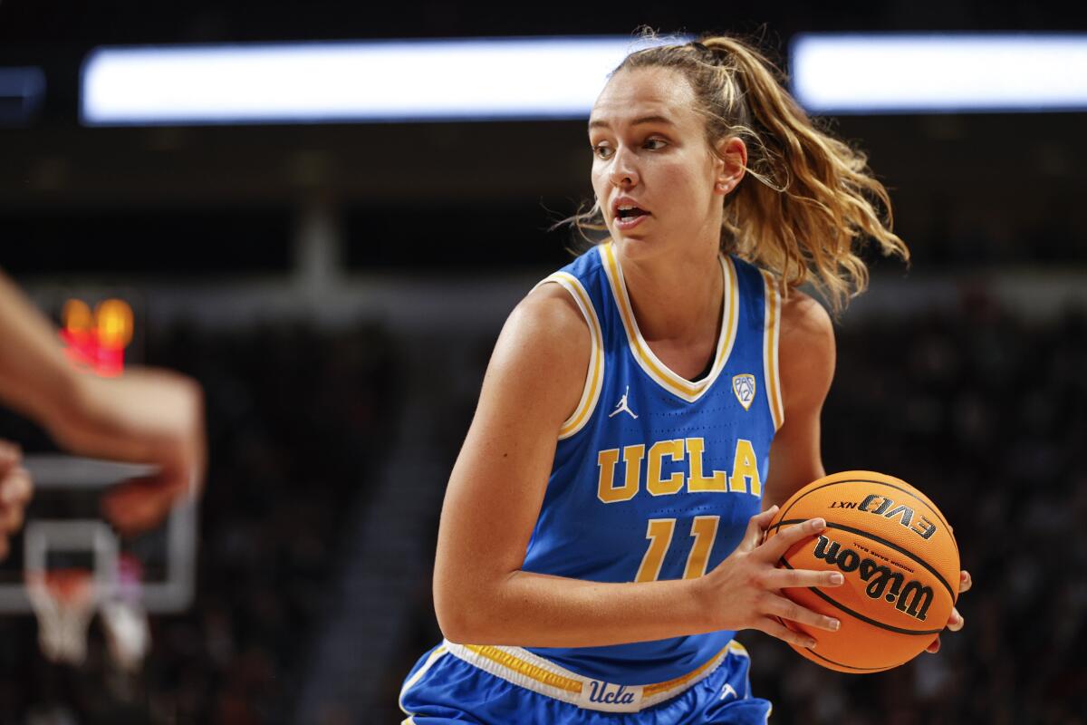 UCLA forward Emily Bessoir holds on to a basketball.