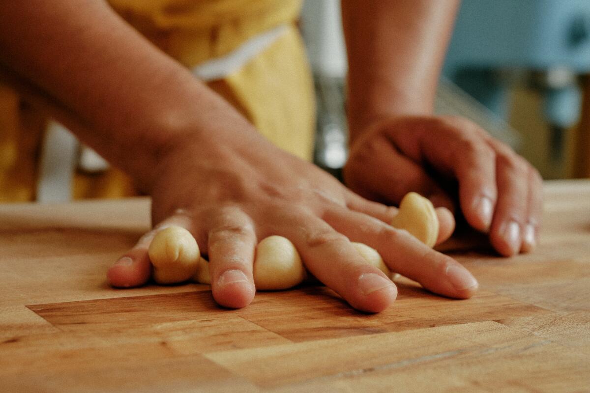 Enciso rolls the dough into a log, pressing down with his spread fingers