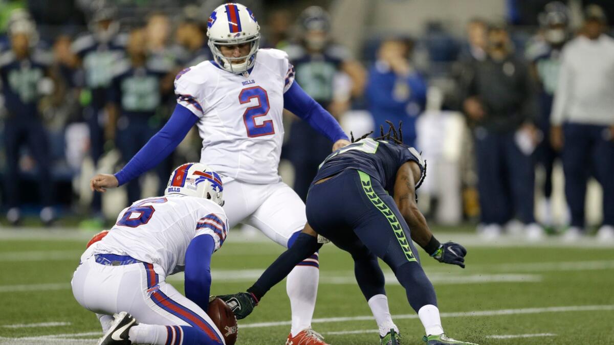 Seattle's Richard Sherman, right, reaches toward the ball as Buffalo's Dan Carpenter attempts to kick and Colton Schmidt holds during "Monday Night Football."