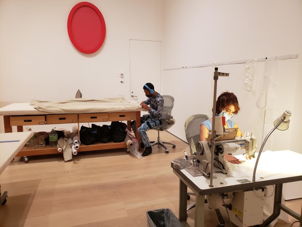 Tailors make clothing in Laura Lima's sewing-room installation, "Alfaiataria"