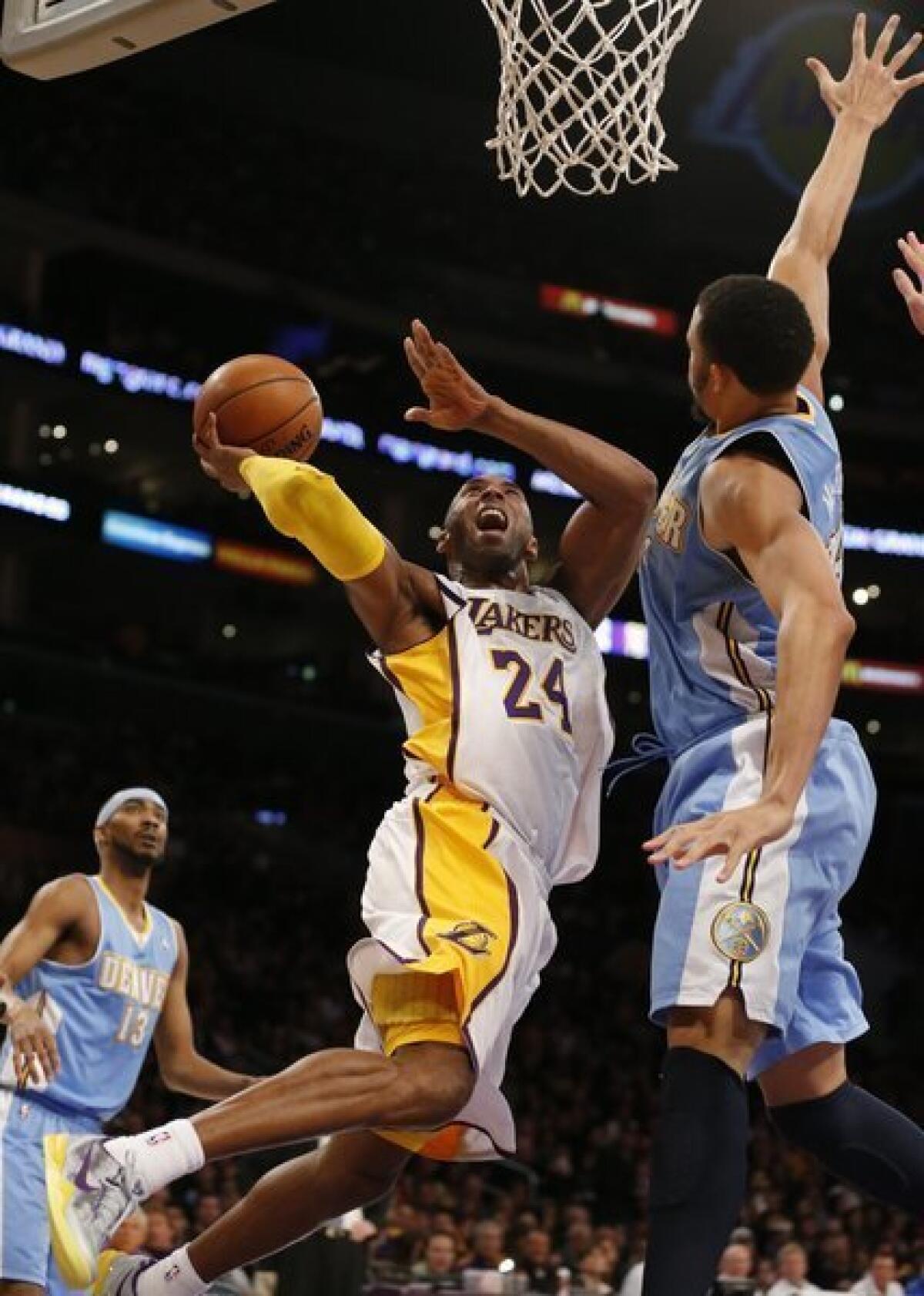 Kobe Bryant contorts his body to shoot over Nuggets defender JaVale McGee.