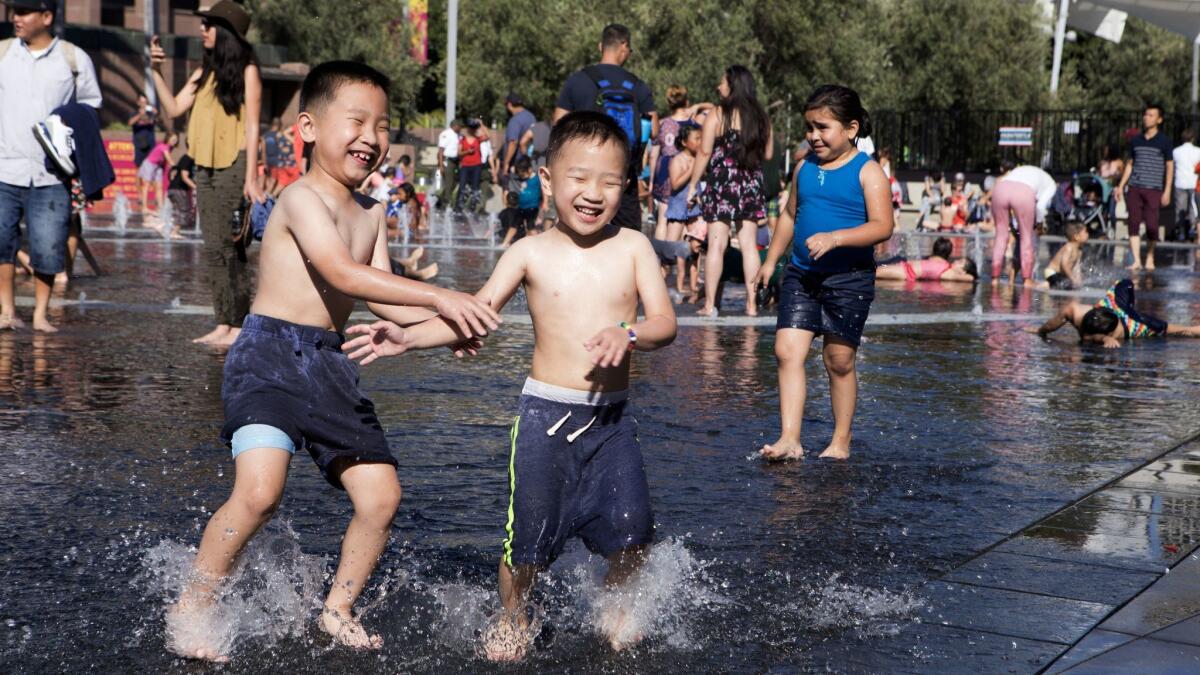 Children play in the fountain at Grand Park during the Fourth of July celebration.